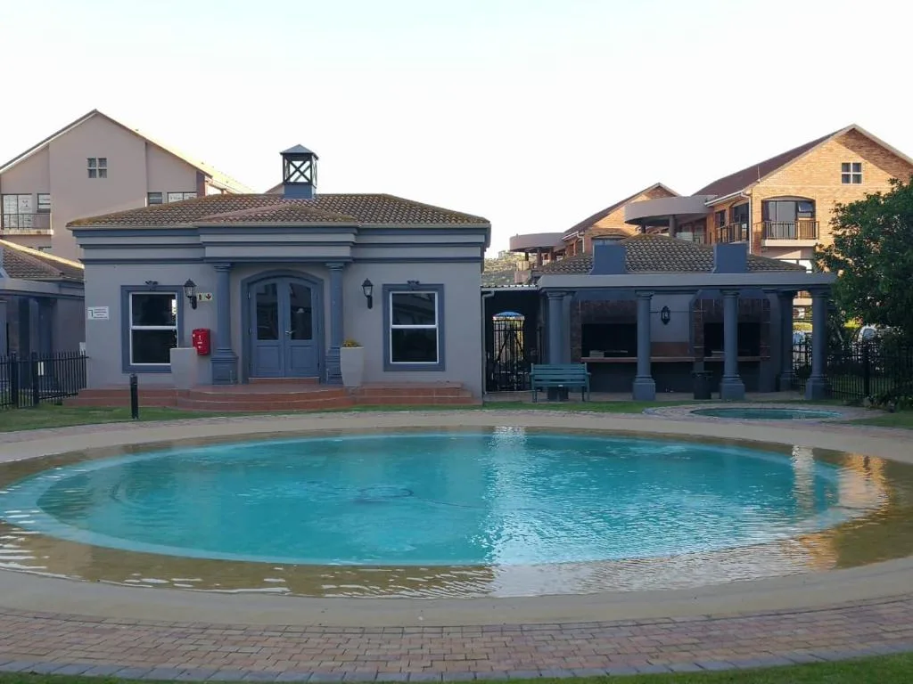 Circular swimming pool with blue water in front of blue-painted building
