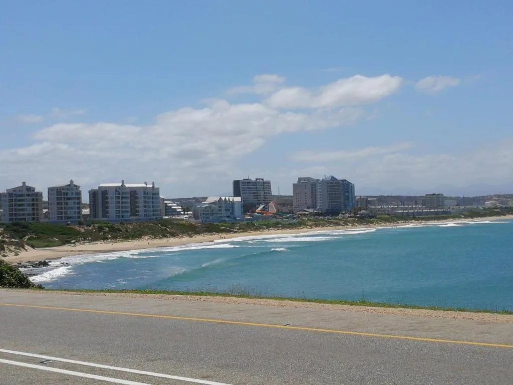 Turquoise ocean beach with coastal town buildings and blue sky