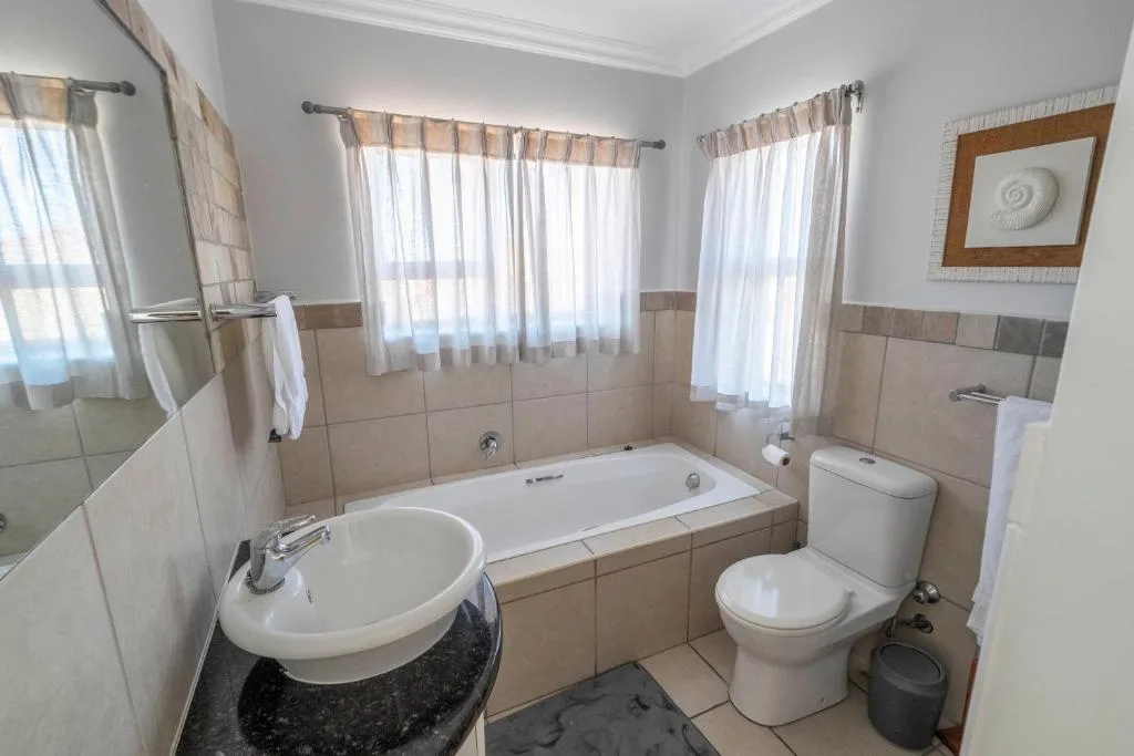 Spacious bathroom with bathtub, sink, toilet, and large windows