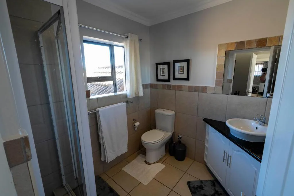 Modern bathroom with shower, toilet, vanity sink, and window with sea views