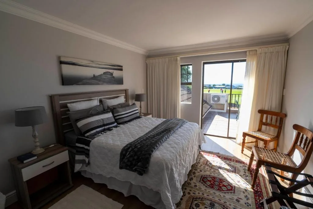 Bright bedroom with queen bed, golf course views through glass doors