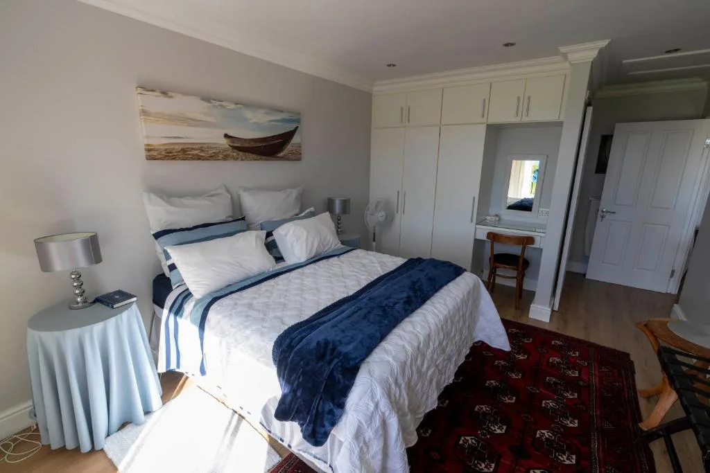 Bright bedroom with queen bed, white built-in wardrobes, and coastal artwork