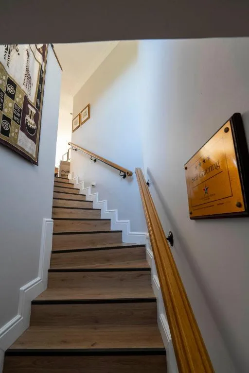 Interior staircase with wooden handrail and framed artwork on walls
