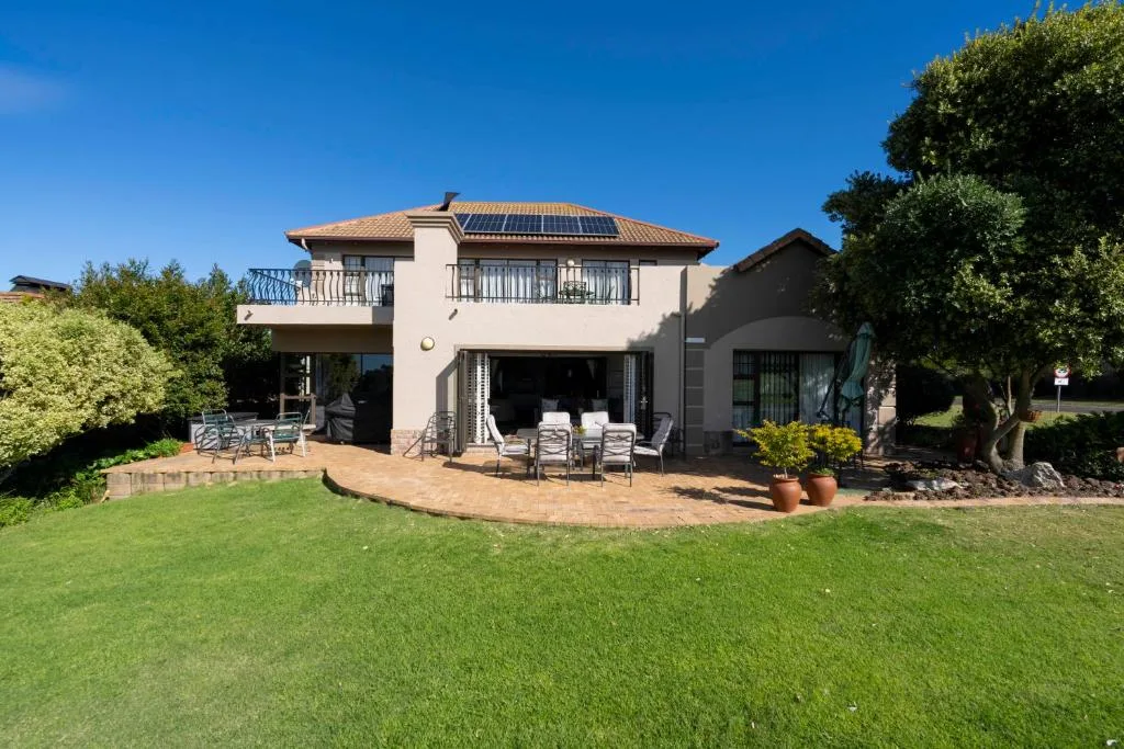 Modern two-story home with manicured lawn and furnished patio area