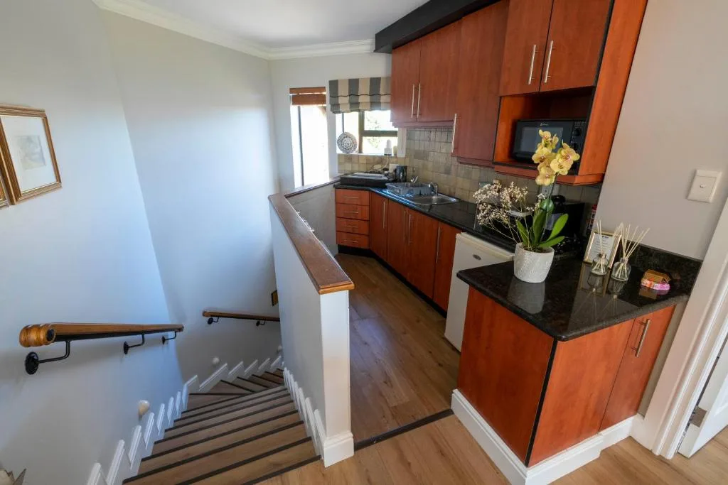 Modern kitchen with wooden cabinets, black countertops, and yellow flowers