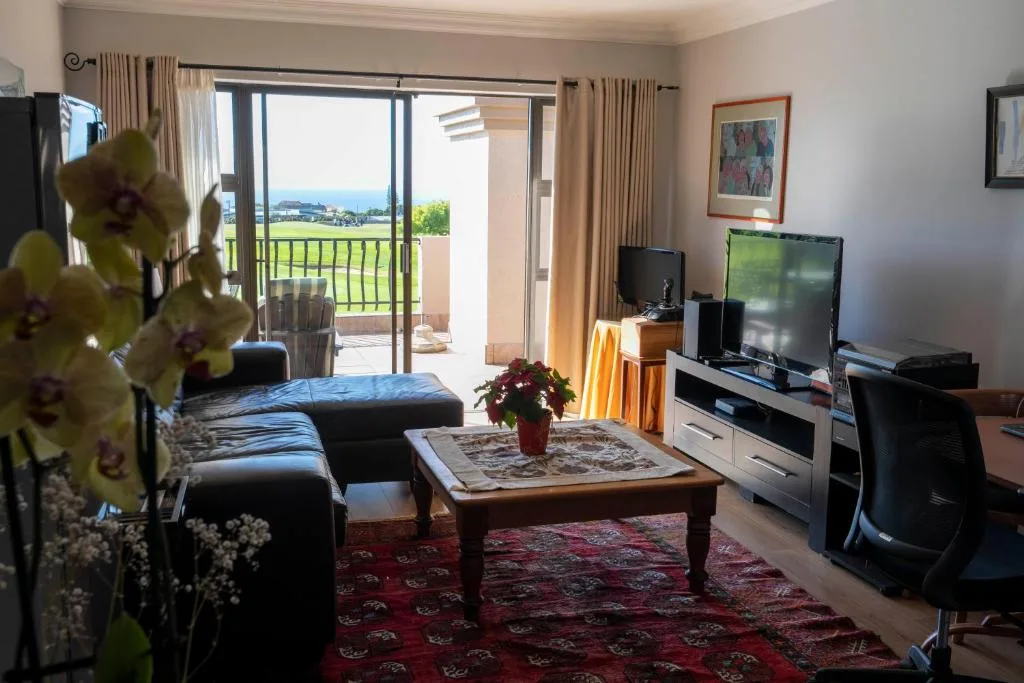 Spacious lounge with black sofa, TV, and garden view through sliding doors