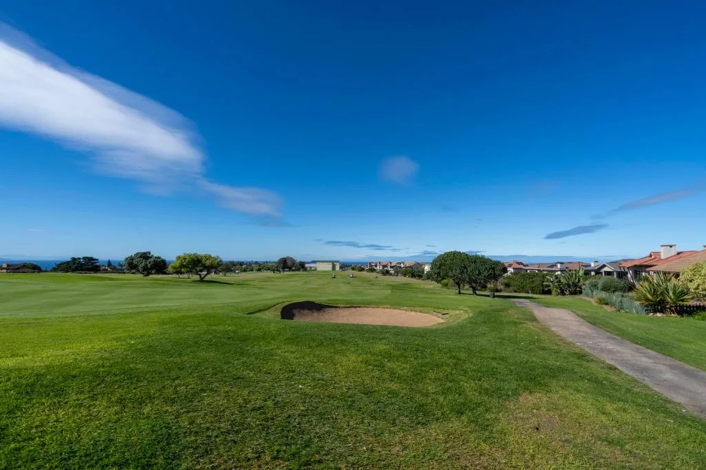 Golf course fairway with sand bunker overlooking distant mountains and town