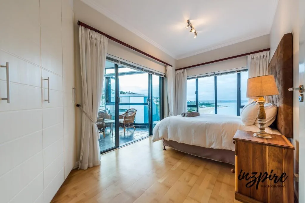Spacious bedroom with ocean view through glass doors and balcony access