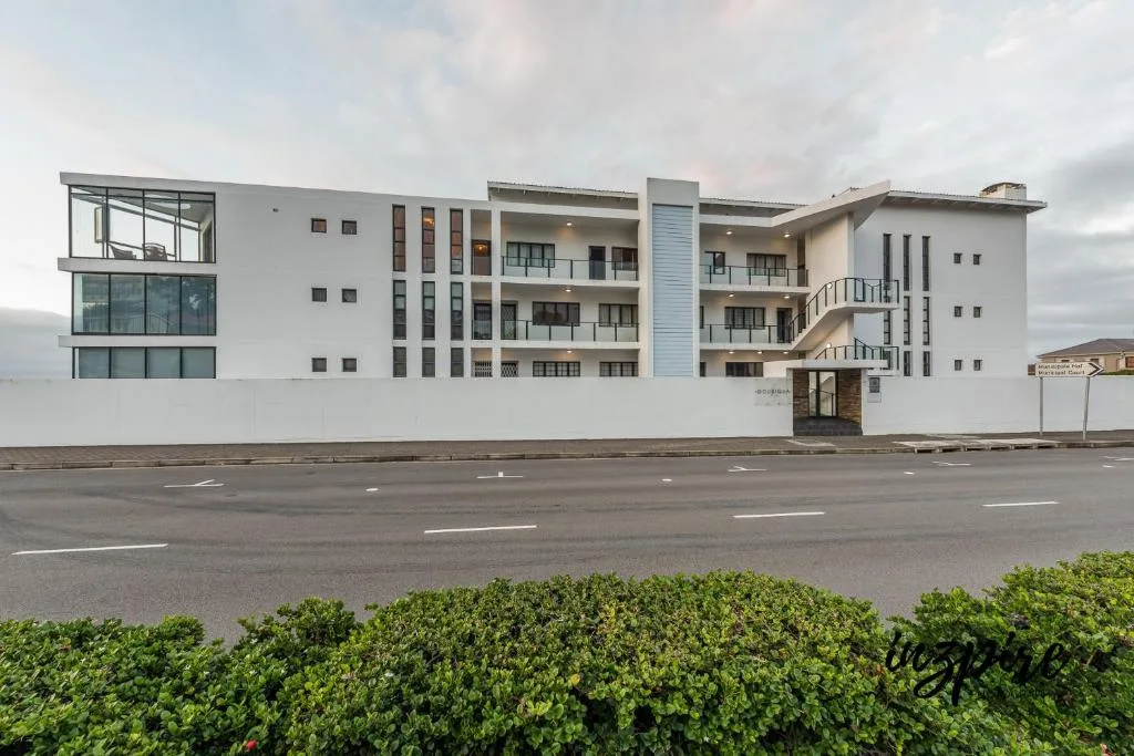 Modern white apartment building facade with multiple balconies and entrance