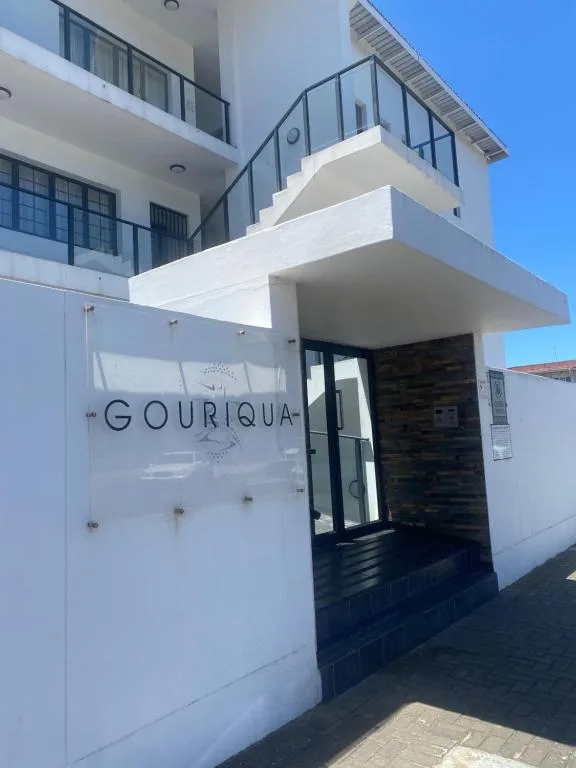 Modern white apartment building entrance with signage and metal railings