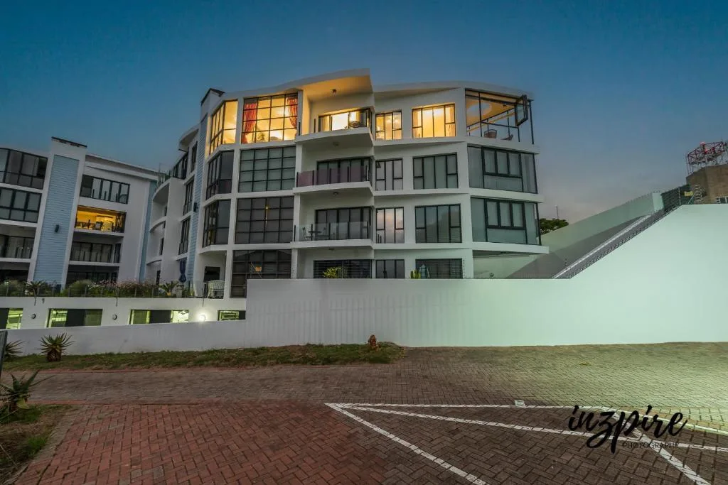 Modern multi-story apartment building with white facade and large windows at dusk