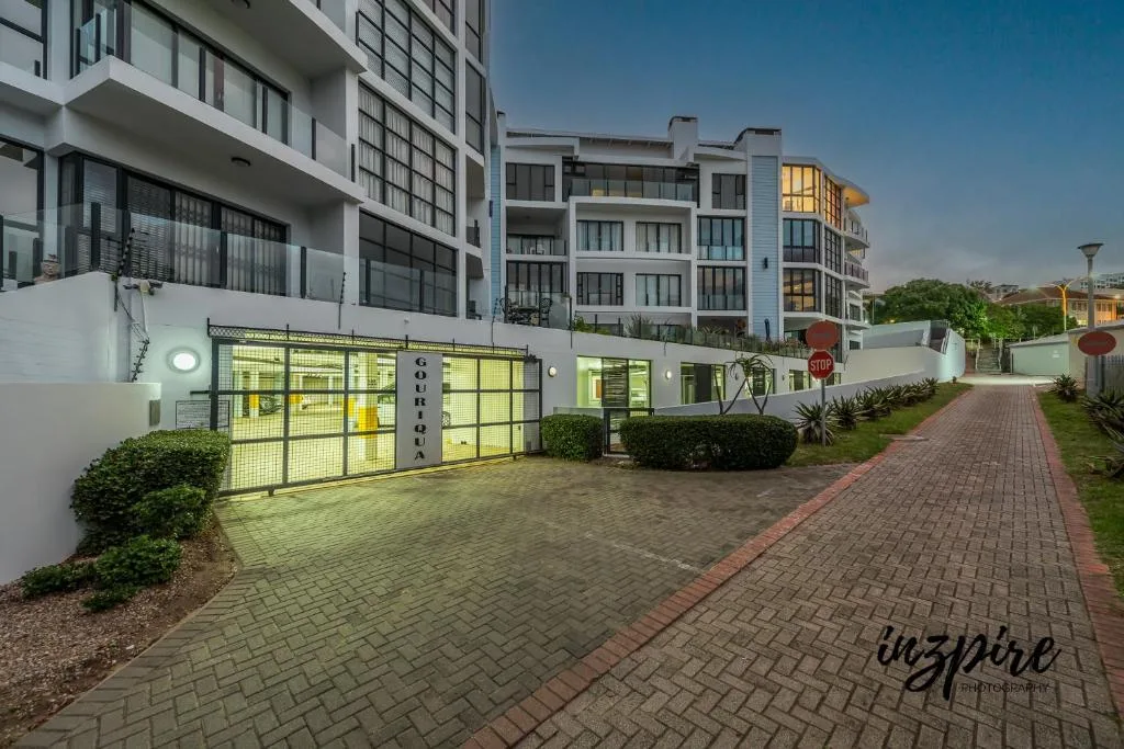 Modern apartment building entrance with yellow garage gates and paved driveway