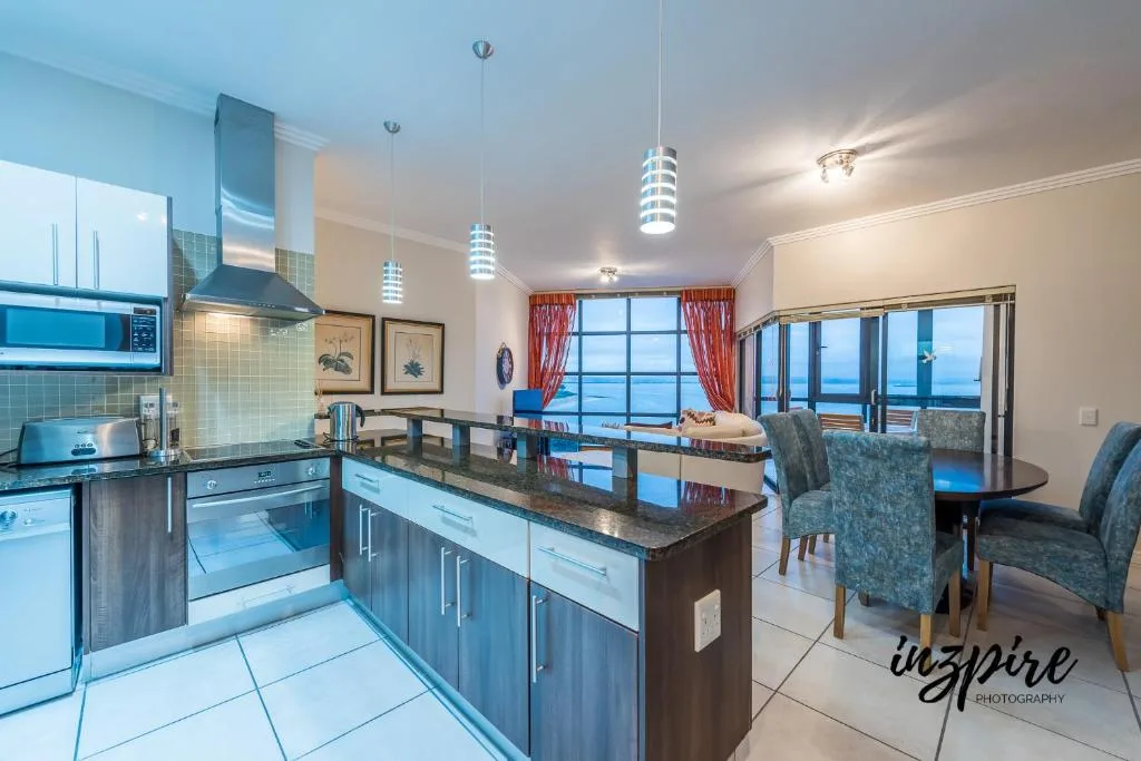 Modern kitchen with island counter, stainless steel appliances, ocean view
