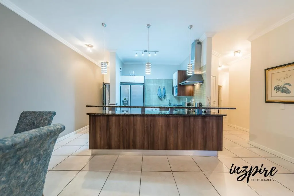 Modern kitchen with dark cabinetry, stainless steel appliances, pendant lights