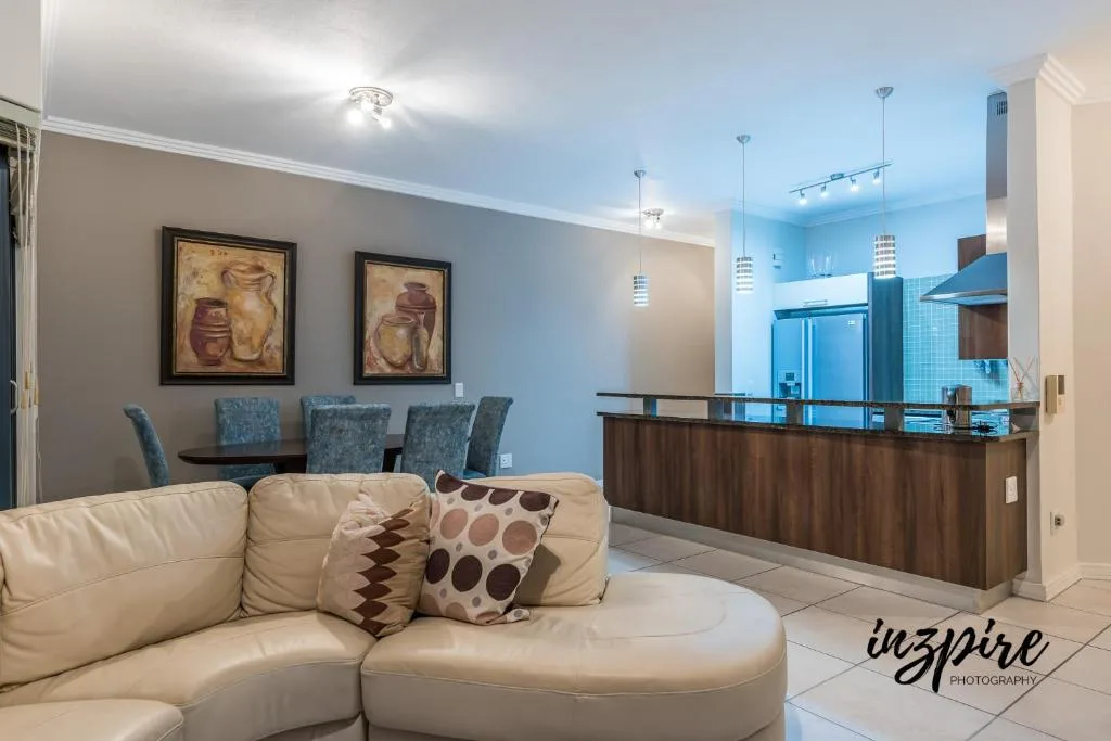 Open-plan lounge with cream sectional sofa and modern kitchen visible behind