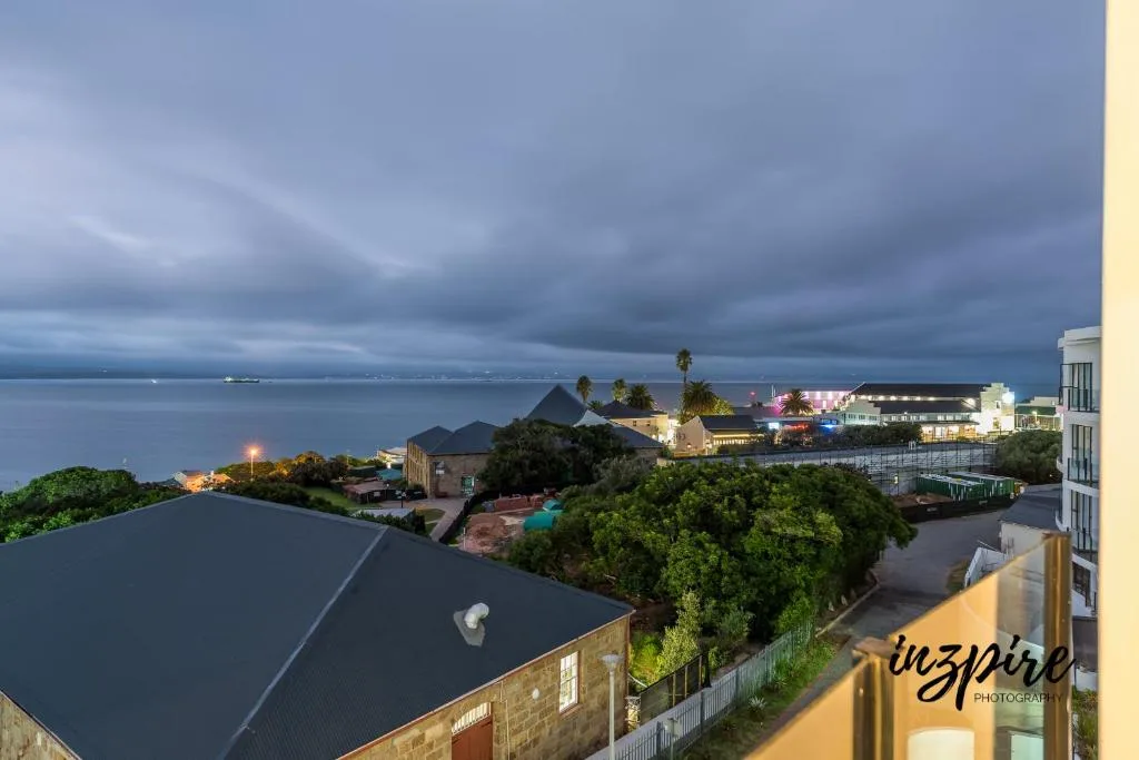 Twilight coastal view overlooking Mossel Bay with illuminated buildings and ocean
