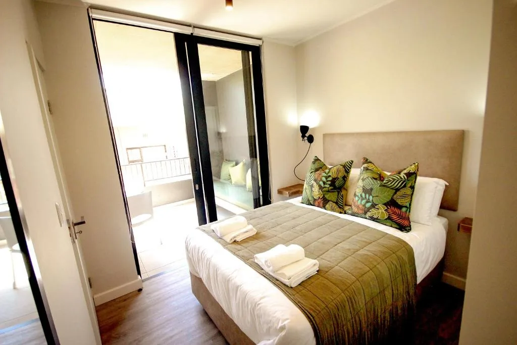 Bright bedroom with queen bed, tropical pillows, and sliding balcony doors