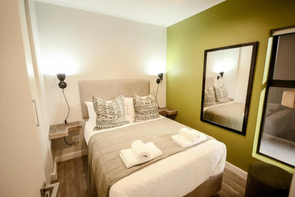 Modern bedroom with queen bed, olive green accent wall, and mirrored wardrobe doors