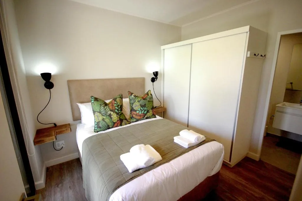 Bright bedroom with double bed, tropical cushions, and built-in wardrobe storage