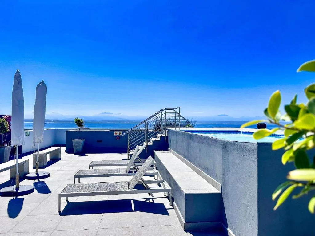 Sunny rooftop deck with loungers overlooking ocean and islands