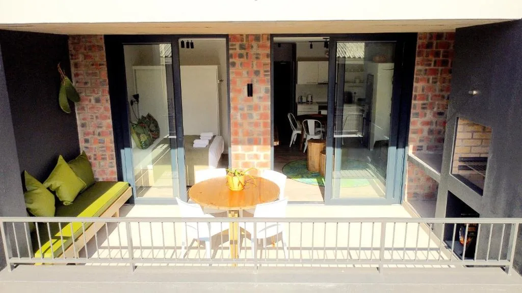 Elevated deck with wooden dining table overlooking brick apartment interior
