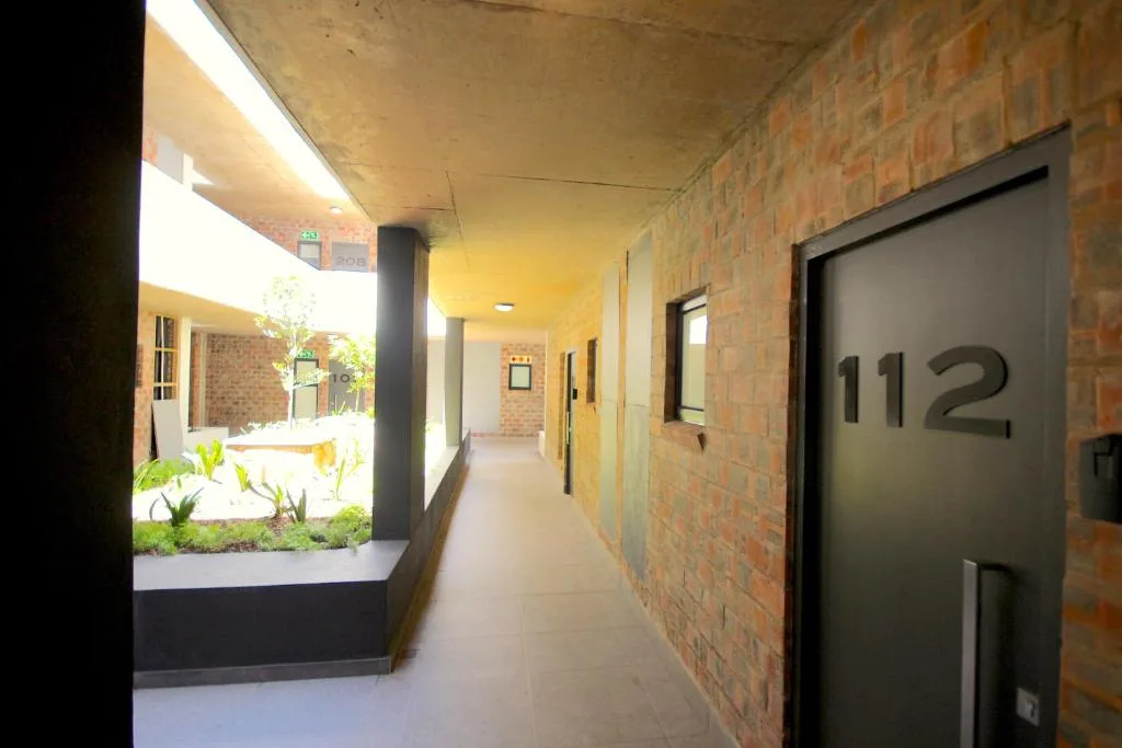 Modern covered breezeway with brick walls and apartment entrance numbered 112