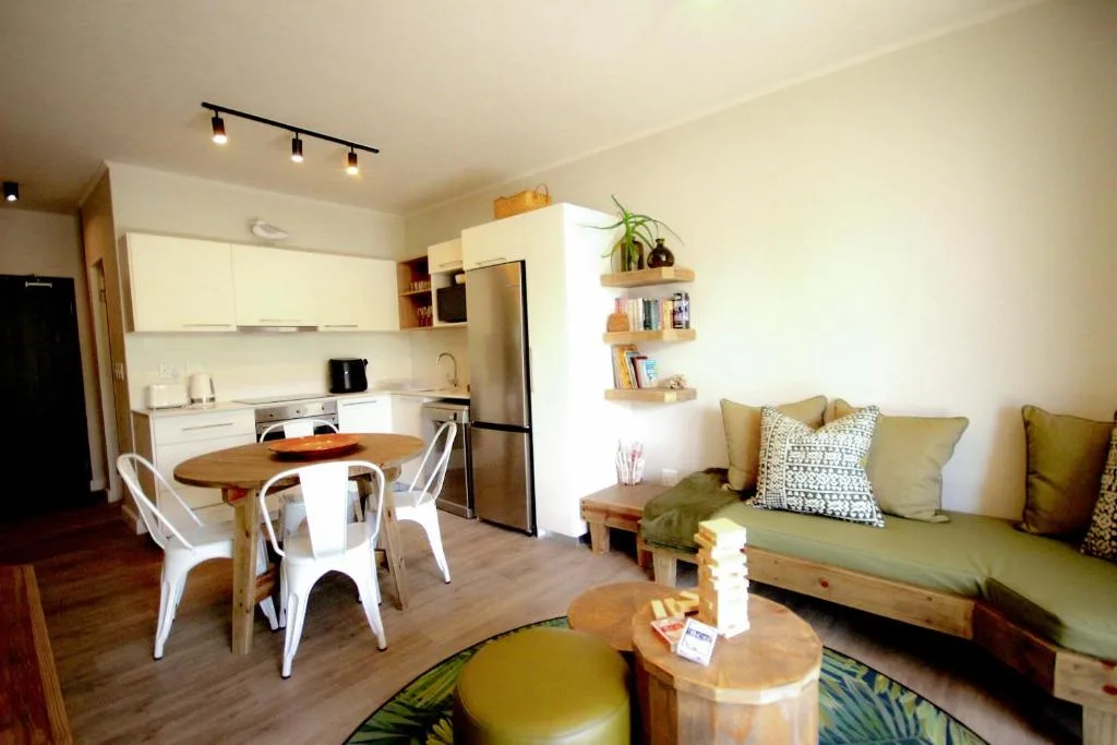 Open-plan lounge with green sofa, wooden coffee table, and modern decor