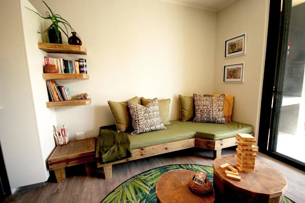 Cozy lounge with green sofa, wooden shelving, books, and patterned pillows