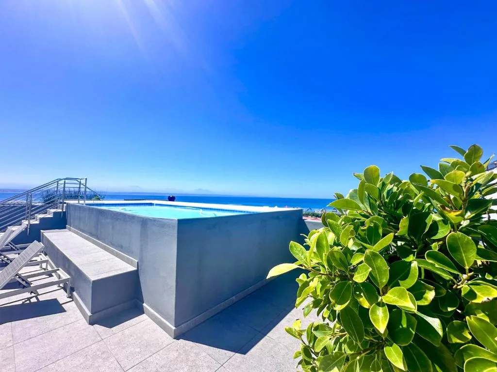 Infinity pool overlooking blue ocean and coastline on sunny day