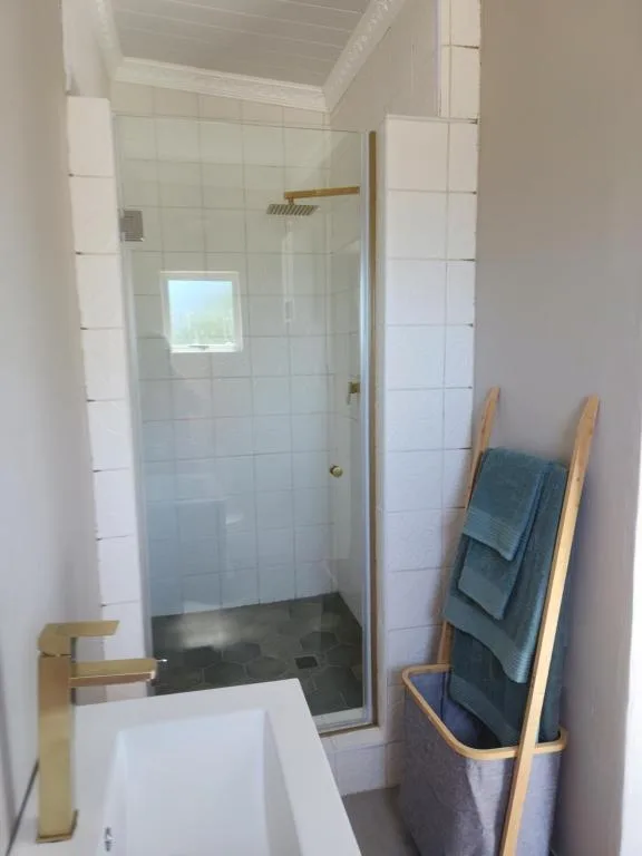 Modern bathroom with walk-in shower, white tiles, and wooden towel rack