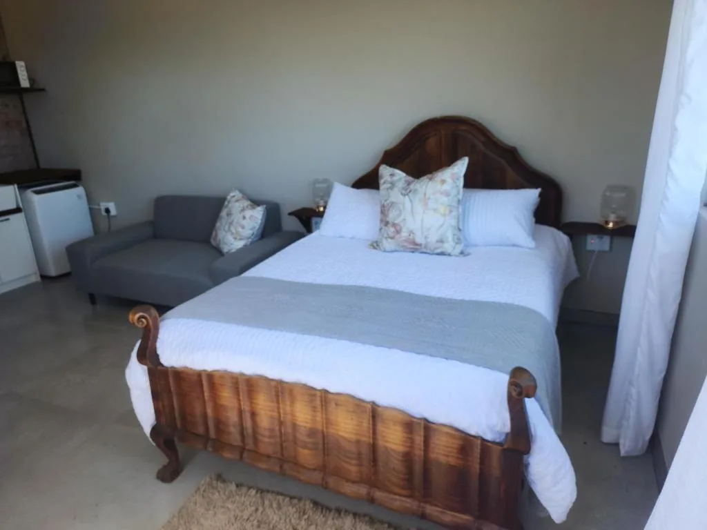 Spacious bedroom with wooden bed, white linens, and comfortable seating area