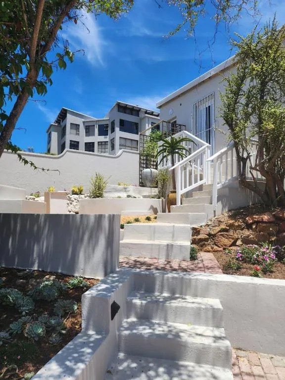 Modern white apartment building with landscaped gardens and stone steps