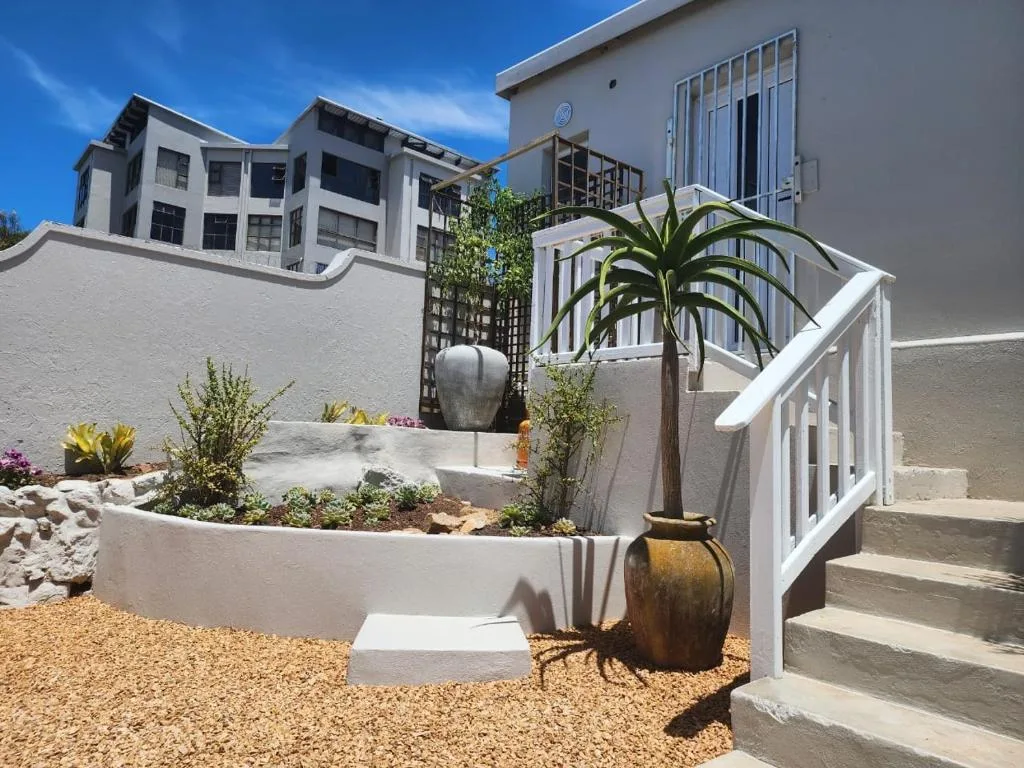 Modern white building entrance with landscaped garden and potted plants