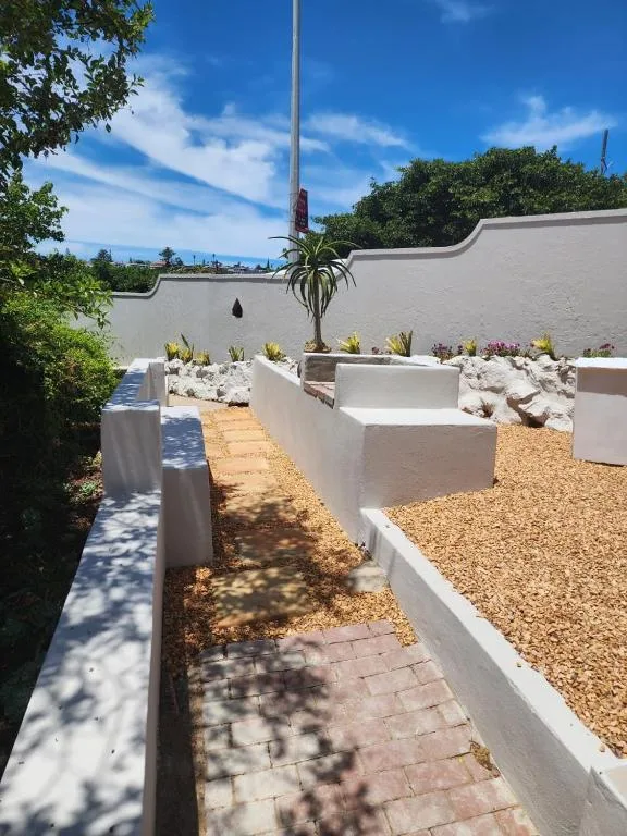 White-walled garden courtyard with potted plants and ocean view beyond