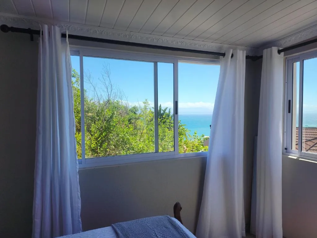 Coastal ocean view through bright bedroom windows with white curtains