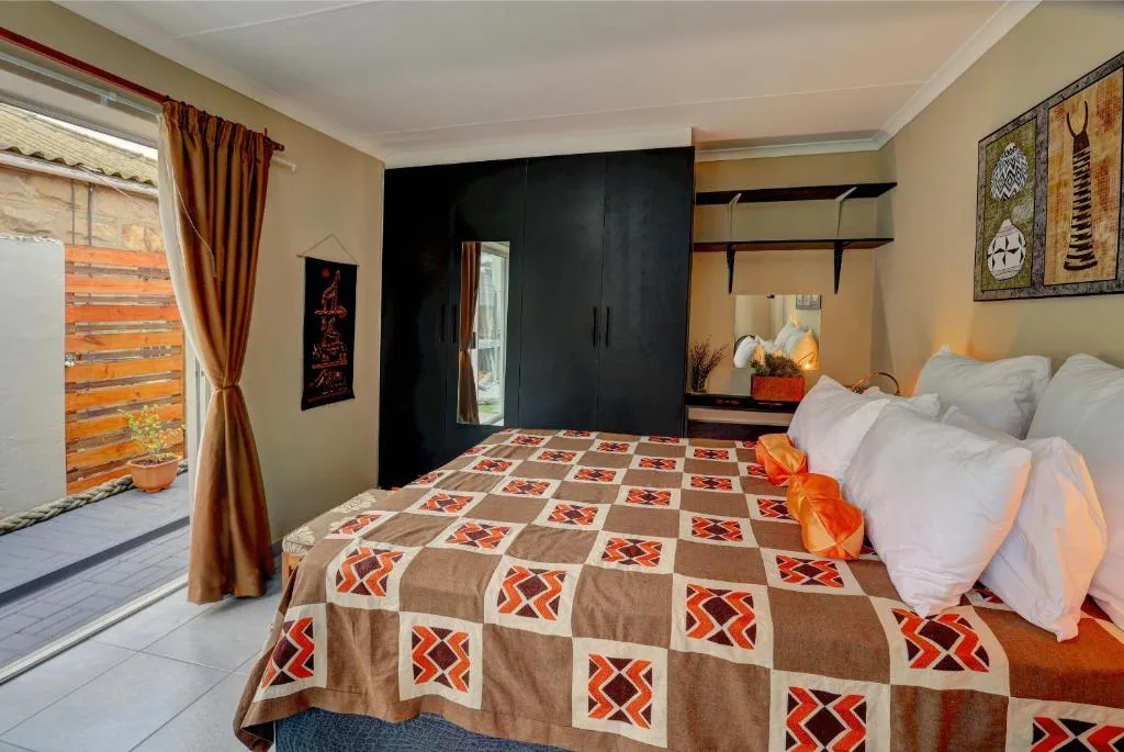 Spacious bedroom with double bed, black wardrobe, and wooden deck access