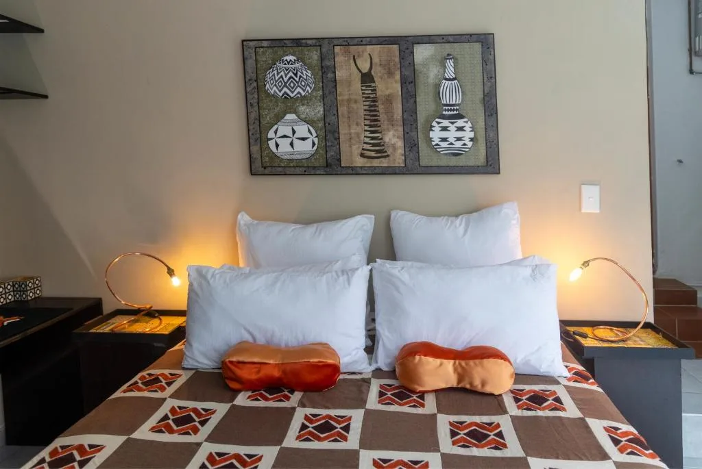 Cozy bedroom with white pillows, patterned bedding, African wall art above