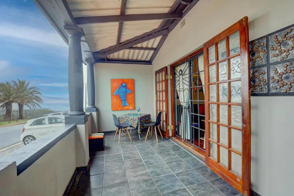 Covered patio with dining table and colorful artwork overlooking street