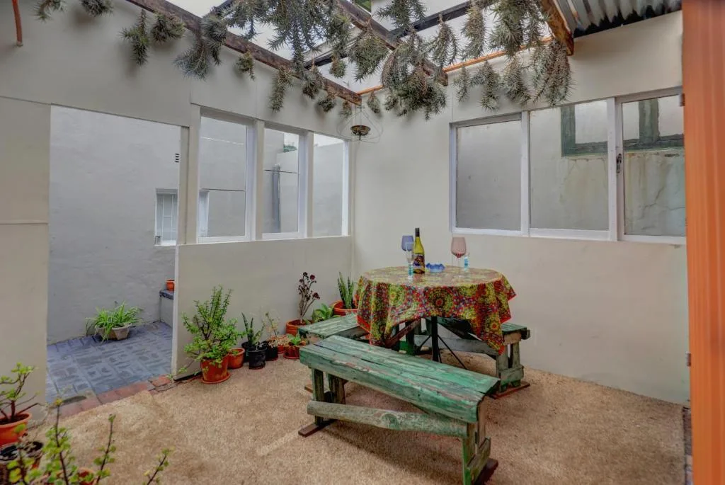 Covered outdoor patio with picnic table, potted plants, and hanging greenery