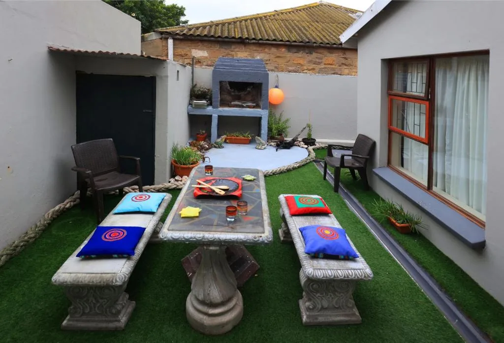 Courtyard with cornhole games, braai area, and outdoor seating on artificial grass