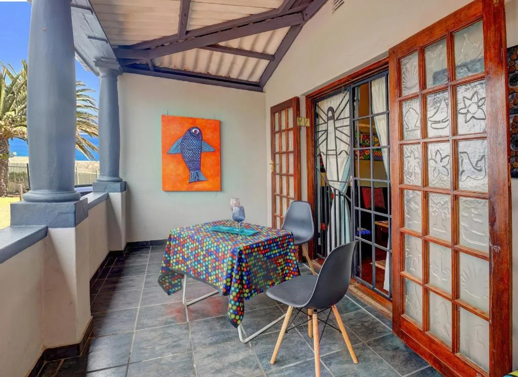 Covered outdoor deck with dining table and sea views