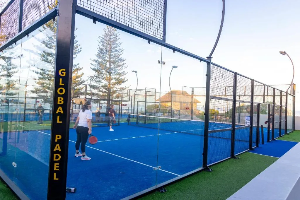 Padel tennis court with blue playing surface and safety netting