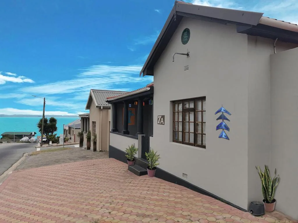 Modern white-walled cottage with brick patio and ocean view in background