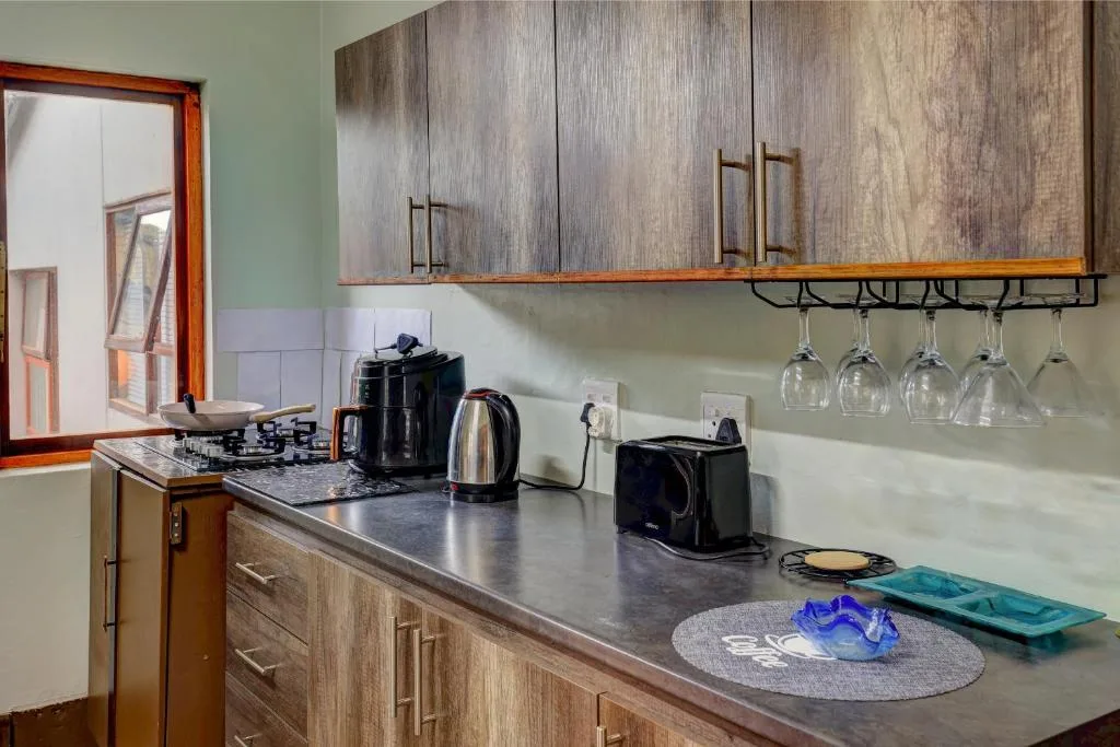 Modern kitchen with gas stove, kettle, and hanging wine glasses