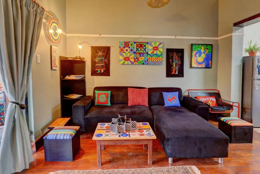 Colorful living room with dark sofa, artwork, and games on wooden floors