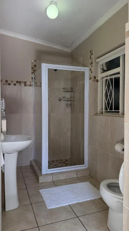 Modern bathroom with shower enclosure, toilet, and pedestal sink