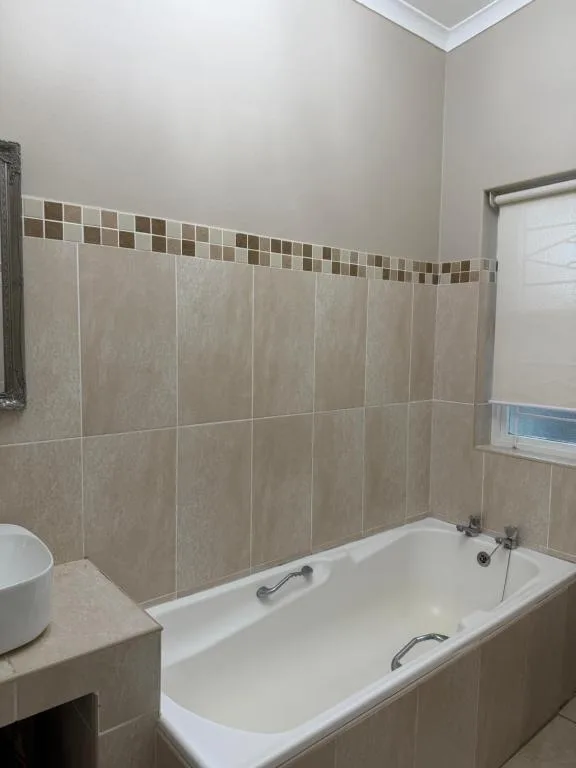 Modern bathroom with white bathtub and neutral tile walls