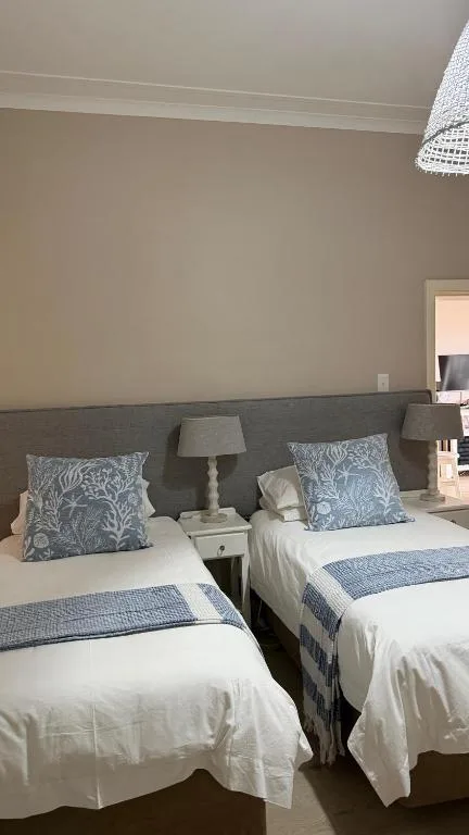 Twin beds with blue patterned cushions and white linens in modern bedroom