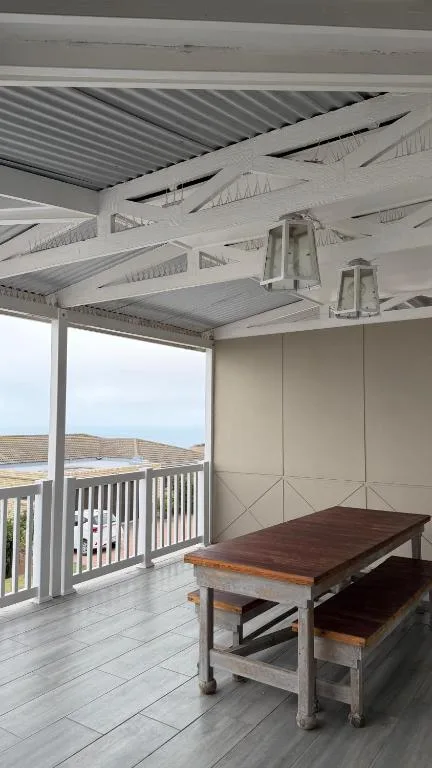 Modern covered deck with dining table and ocean view railing