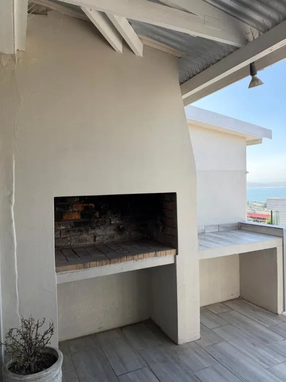 Outdoor braai area with fireplace on covered deck overlooking ocean